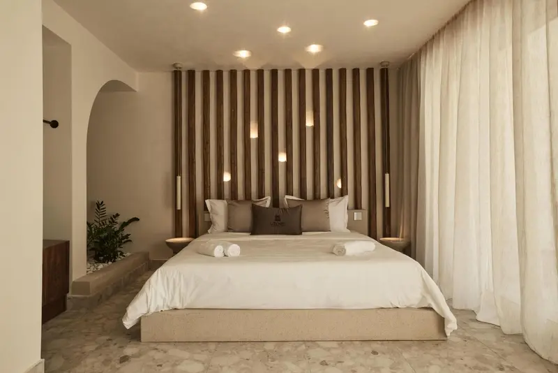 Une chambre lumineuse avec un grand lit recouvert de coussins et de couvertures blanches.