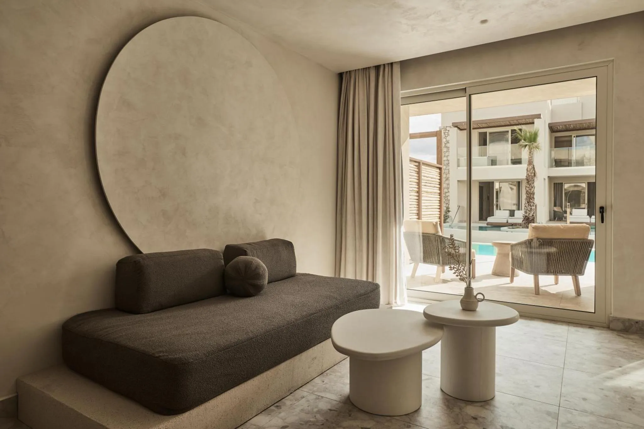 Espace de détente intérieur avec canapé et table basse, donnant sur une terrasse et une piscine.