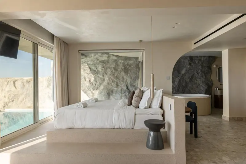 Une chambre lumineuse avec un grand lit et une baignoire intégrée.