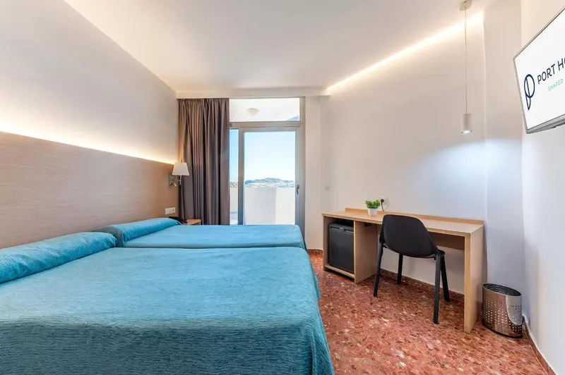 Une chambre lumineuse avec un lit double et un bureau.