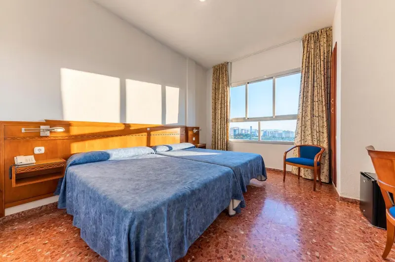Une chambre lumineuse avec deux lits simples et une fenêtre.