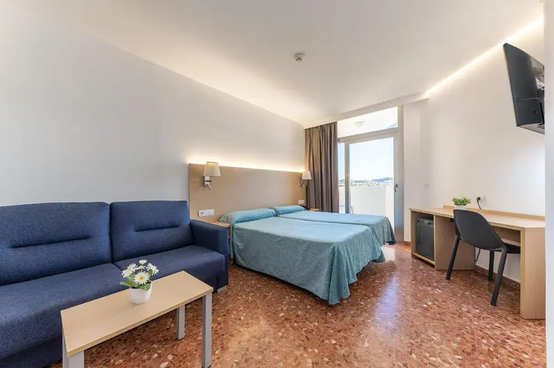 Une chambre lumineuse avec un canapé, un lit et un bureau.