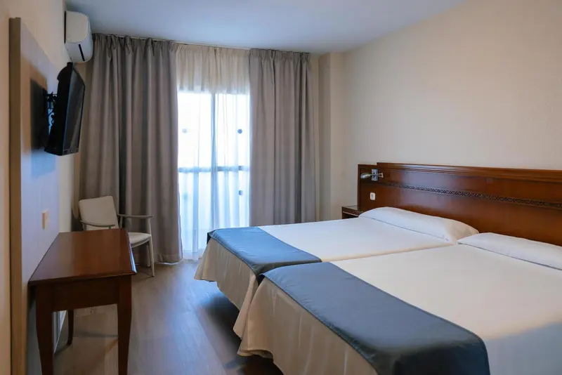 Une chambre d'hôtel lumineuse avec un lit double et un bureau.