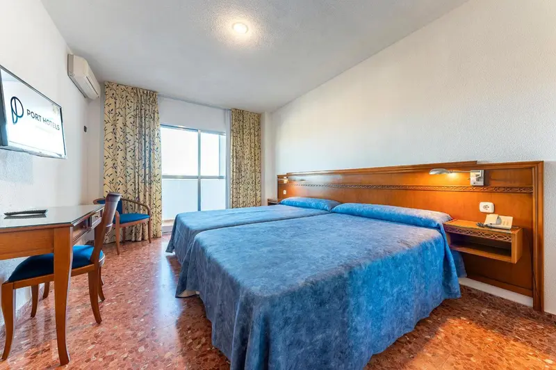 Chambre d'hôtel avec deux lits simples et bureau.