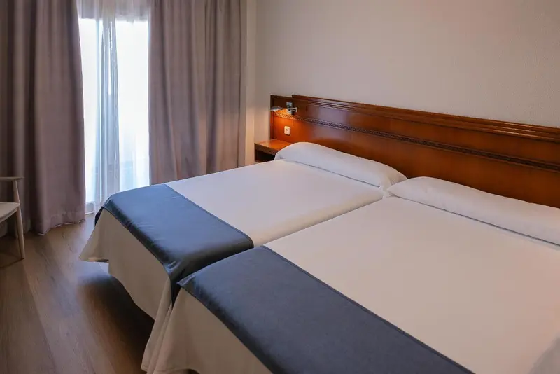 Une chambre avec deux lits simples et une fenêtre.