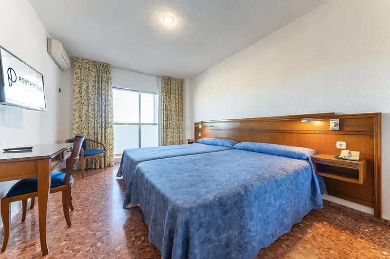 Une chambre d'hôtel lumineuse avec deux lits simples et un bureau.