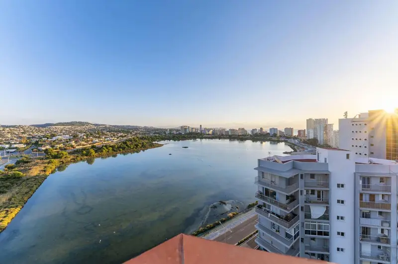 Vue panoramique sur une ville côtière et une lagune au soleil couchant.