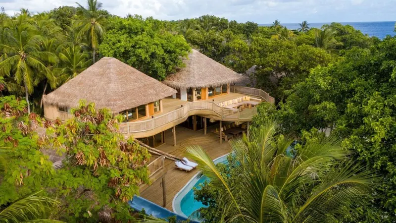 Vue aérienne de bungalows sur pilotis avec terrasse et piscine.