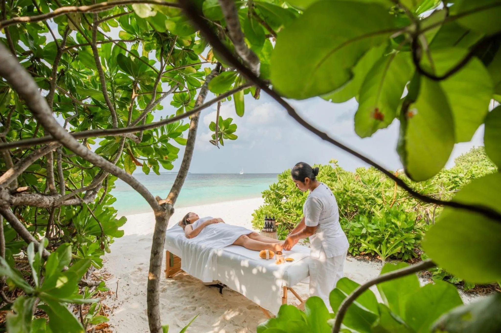 Deux personnes allongées sur des tables de massage en bord de mer.