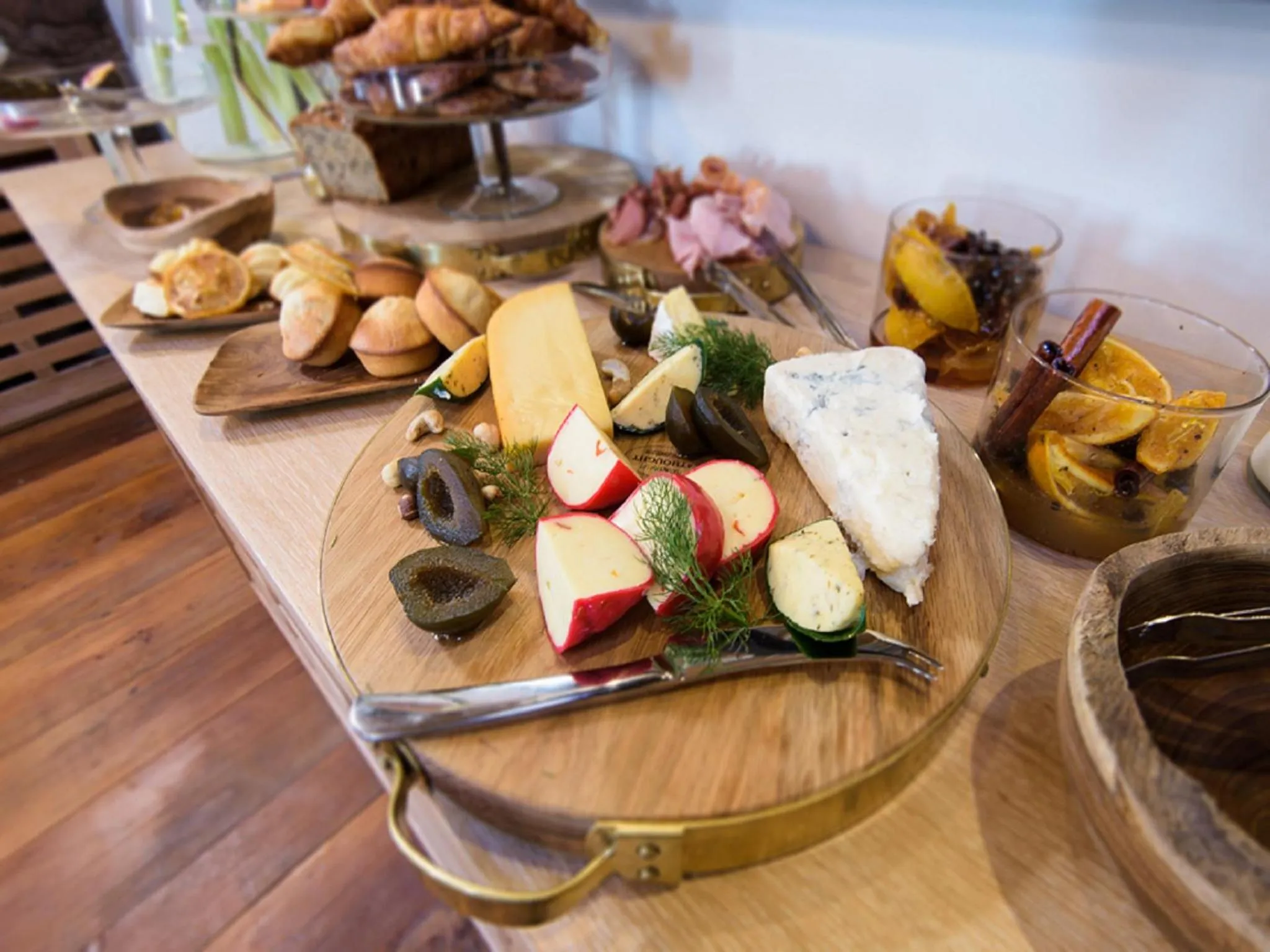 Présentation de charcuterie, fromages et viennoiseries sur un buffet.
