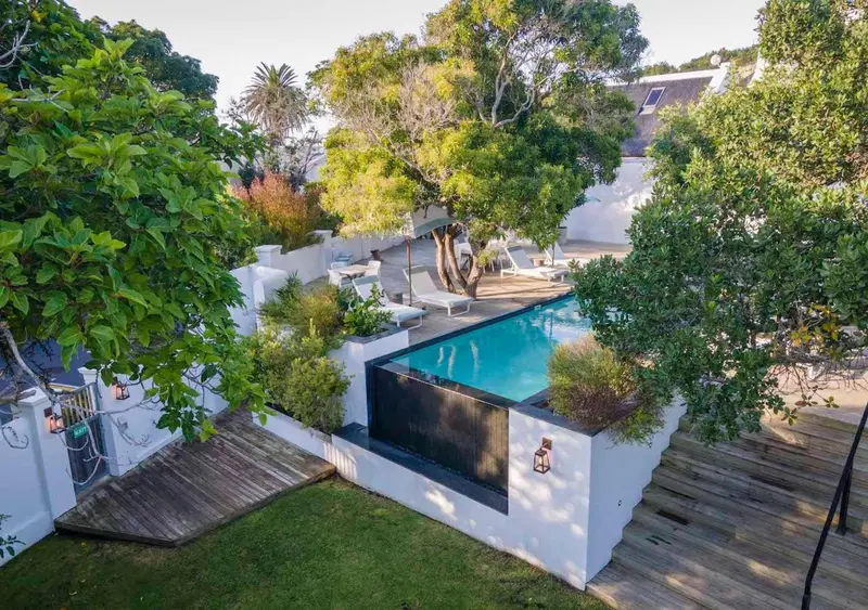 Une piscine rectangulaire bordée de chaises longues et de végétation luxuriante.