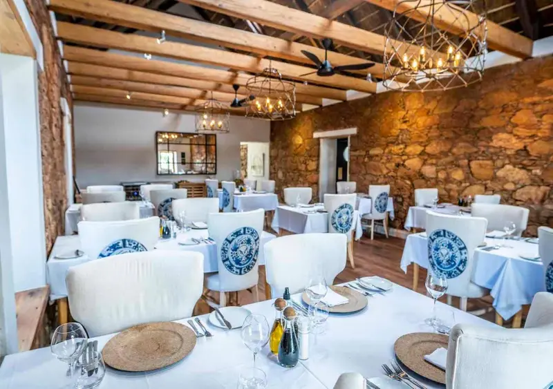 Une salle de restaurant lumineuse avec des tables dressées et des chaises blanches.