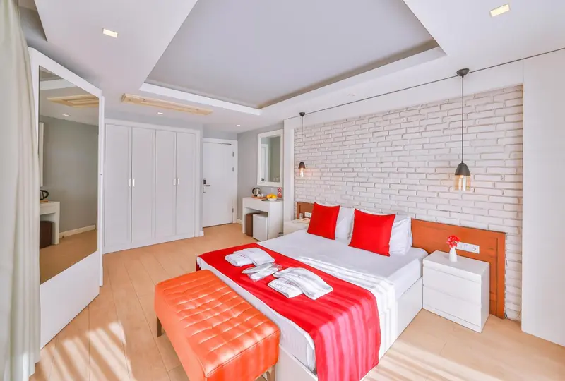 Chambre lumineuse avec un grand lit et un mur en briques blanches.
