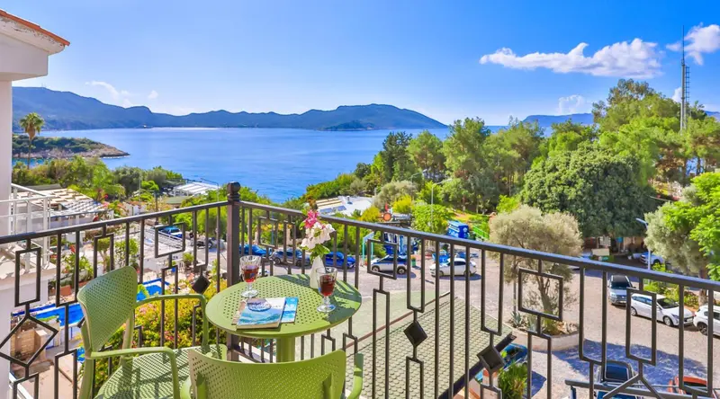 Une terrasse avec une table et des chaises offre une vue sur la mer et les montagnes.