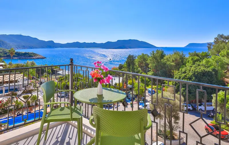 Une terrasse avec table et chaises offre une vue sur la mer et les montagnes.
