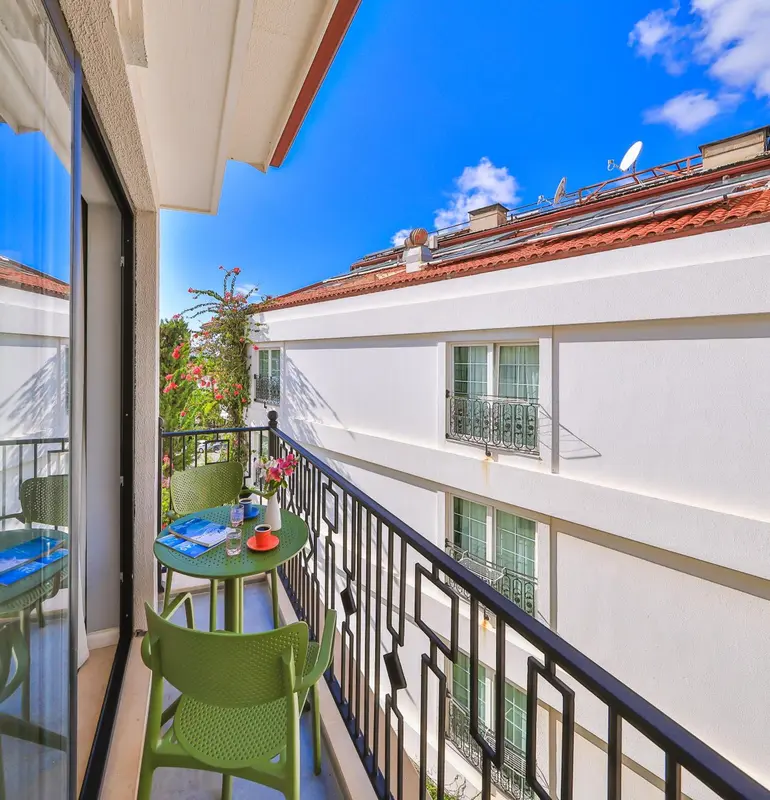 Une terrasse avec une table et des chaises offre une vue sur les toits et la végétation.