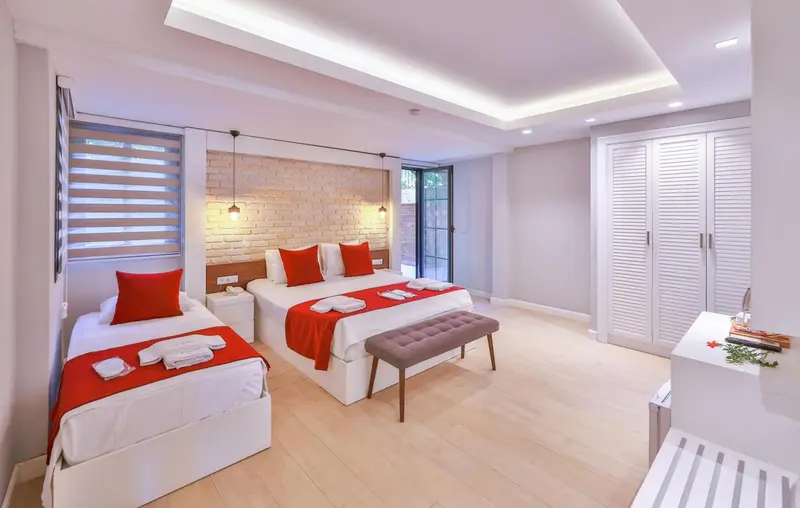 Chambre lumineuse avec lits jumeaux et décoration rouge.
