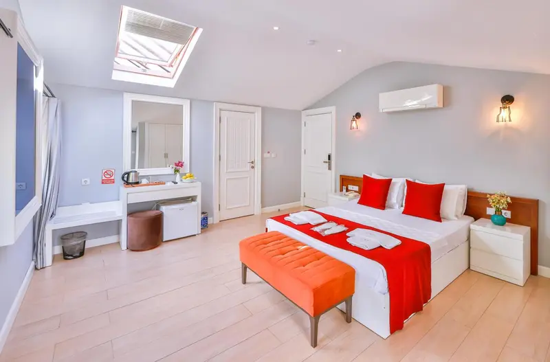 Une chambre lumineuse avec un lit double et un coin coiffeuse.