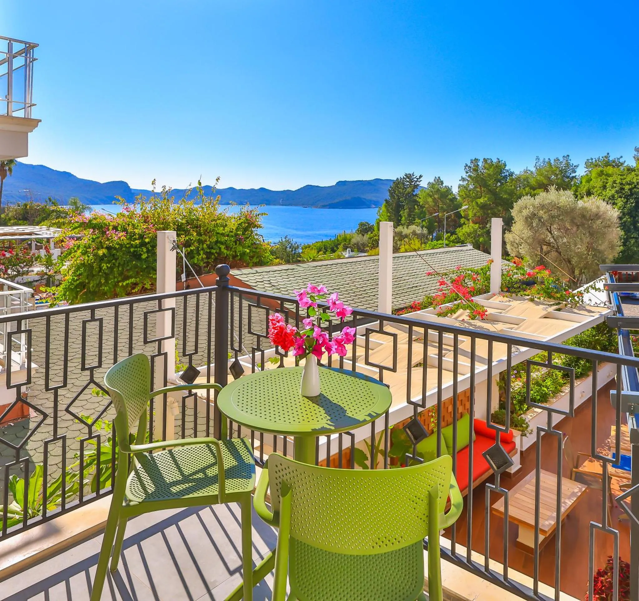 Une terrasse avec une table et des chaises offre une vue sur la mer et les montagnes.