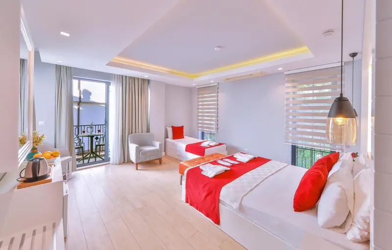 Chambre lumineuse avec deux lits simples et un coin salon.