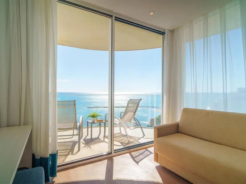 Espace de détente lumineux avec vue sur la mer depuis un balcon.