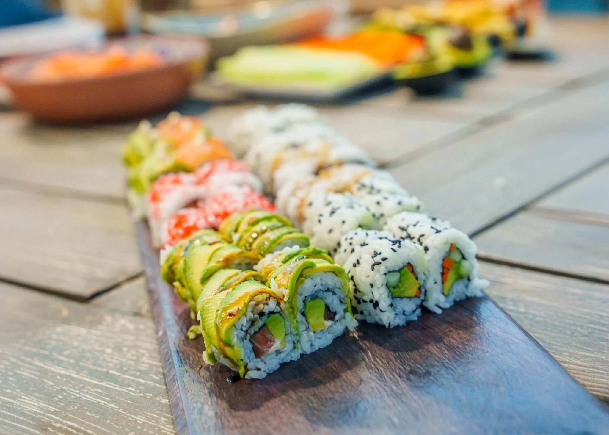 Assortiment de makis colorés présentés sur une planche en bois.