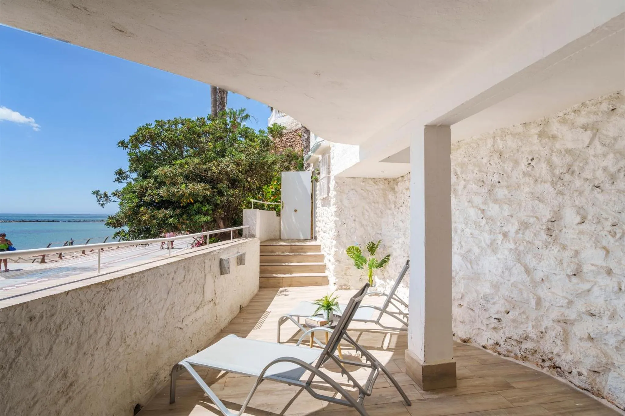 Terrasse ombragée avec transats donnant sur la mer.
