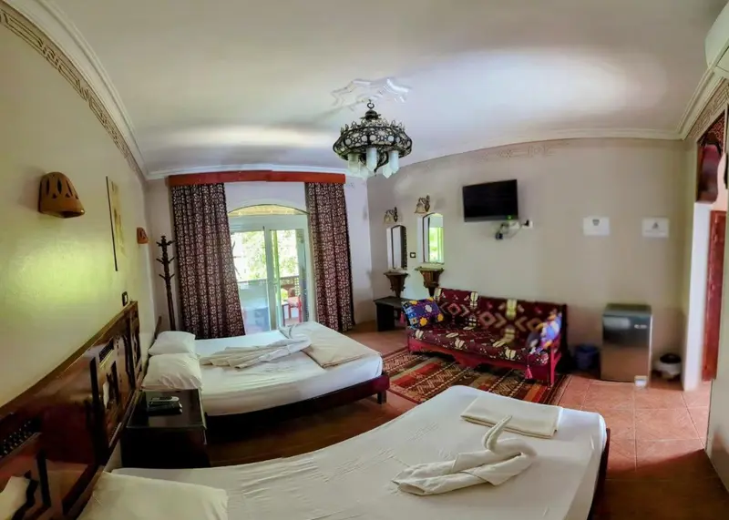 Chambre lumineuse avec deux lits et un coin salon.