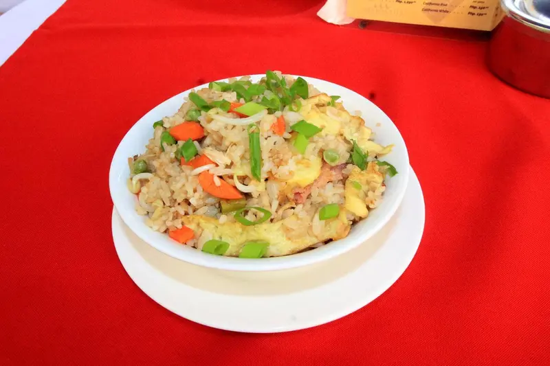 Assiette de riz frit aux légumes et aux œufs sur une nappe rouge.