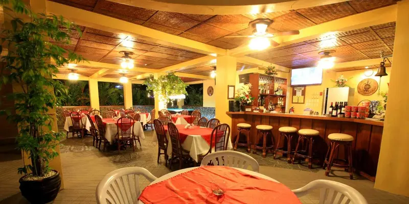 Une salle à manger extérieure avec un bar et des tables dressées.
