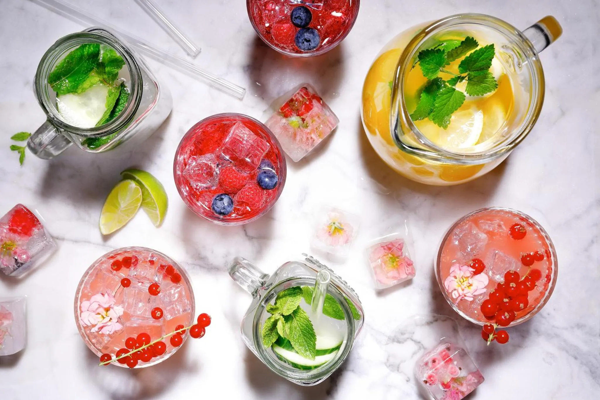 Boissons rafraîchissantes aux fruits et aux glaçons sur un marbre blanc.