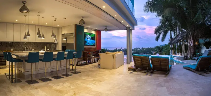 Une cuisine moderne ouverte sur une terrasse avec vue sur la mer et une piscine.