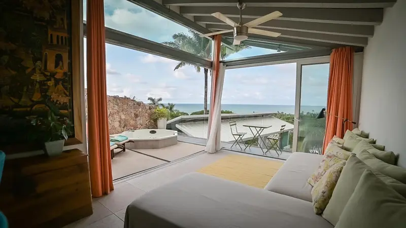 Espace de détente intérieur avec vue sur une terrasse et la mer.