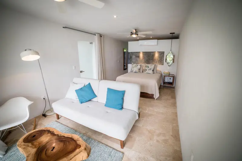 Une chambre lumineuse avec un canapé blanc et un grand lit.
