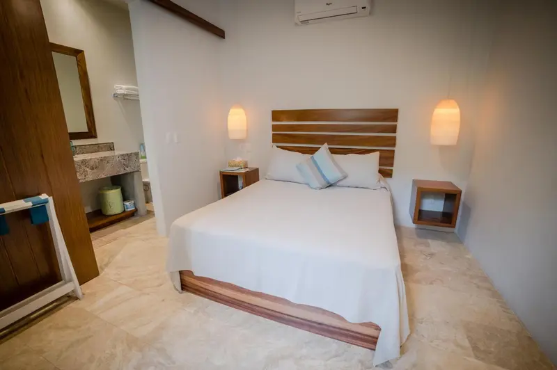 Une chambre lumineuse avec un grand lit et une salle de bain ouverte.