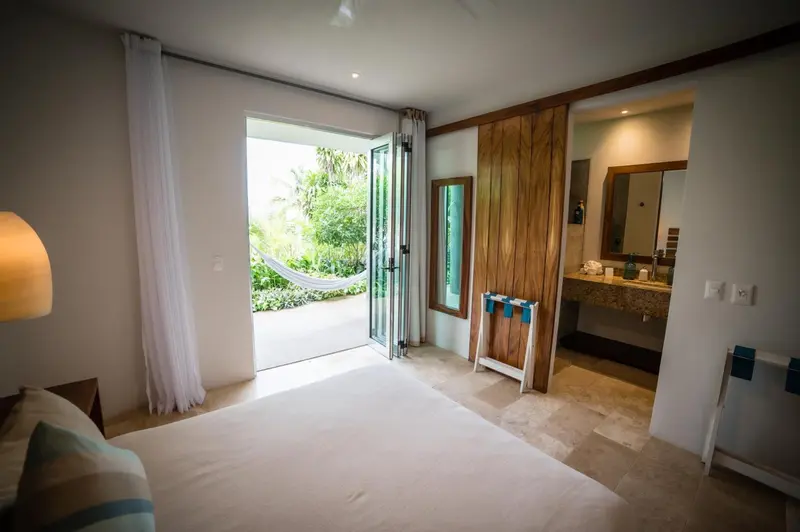 Une chambre lumineuse s'ouvre sur une terrasse avec un hamac.