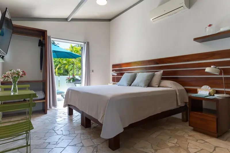Une chambre lumineuse avec un lit double et une vue sur une terrasse.