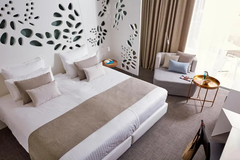 Une chambre lumineuse avec un grand lit et un coin salon.