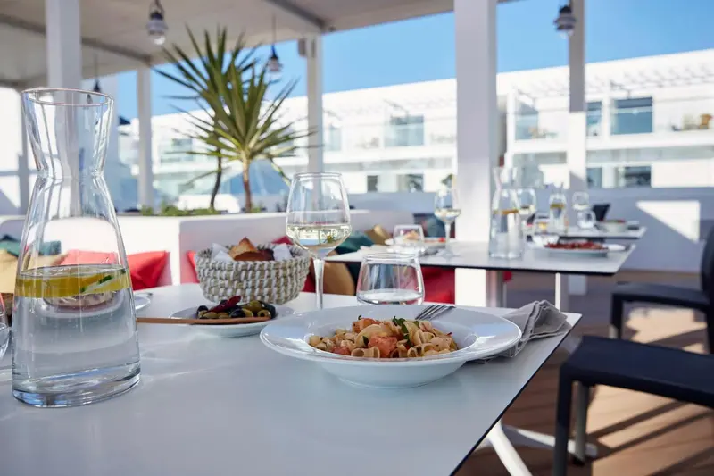 Une table est dressée avec des plats et des boissons sur une terrasse.