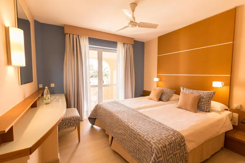 Une chambre lumineuse avec un grand lit et un accès à un balcon.