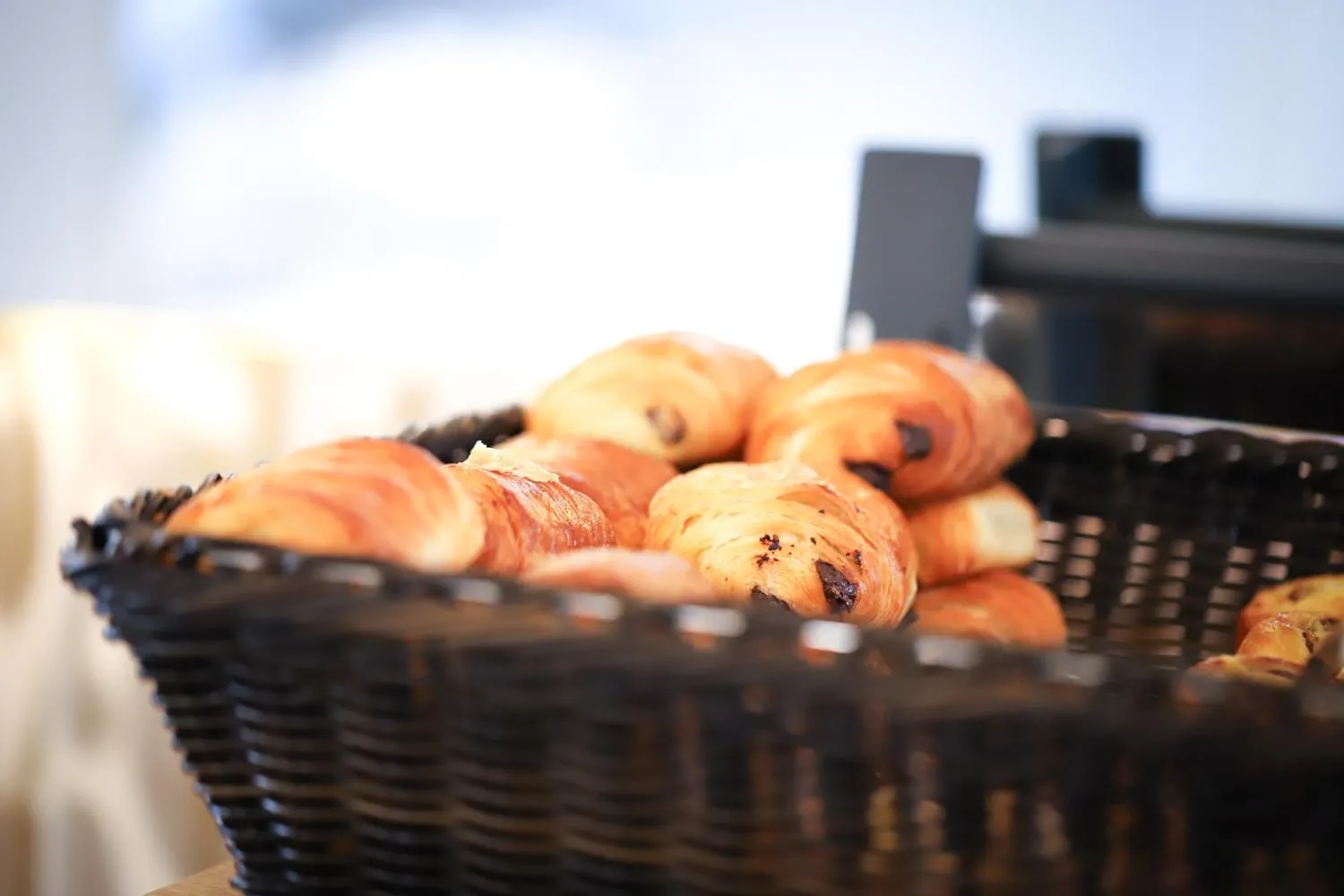 Un panier de viennoiseries est présenté sur un comptoir.