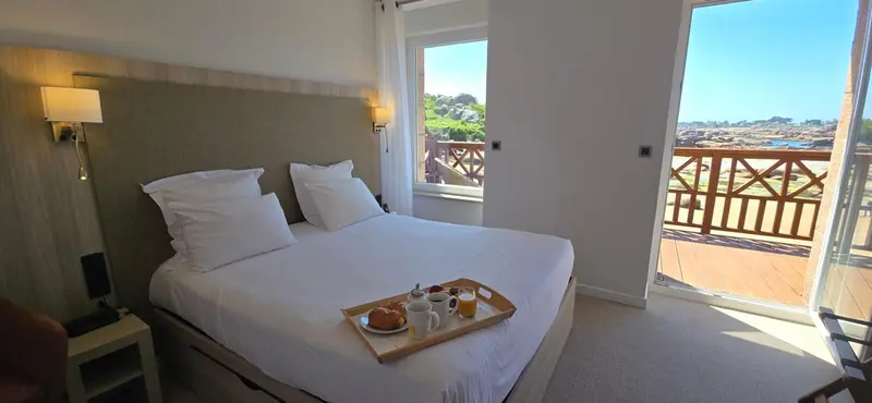 Une chambre lumineuse avec un lit fait et un plateau de petit-déjeuner.