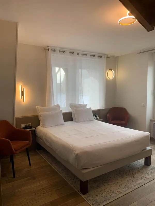 Une chambre lumineuse avec un grand lit recouvert de linge blanc.