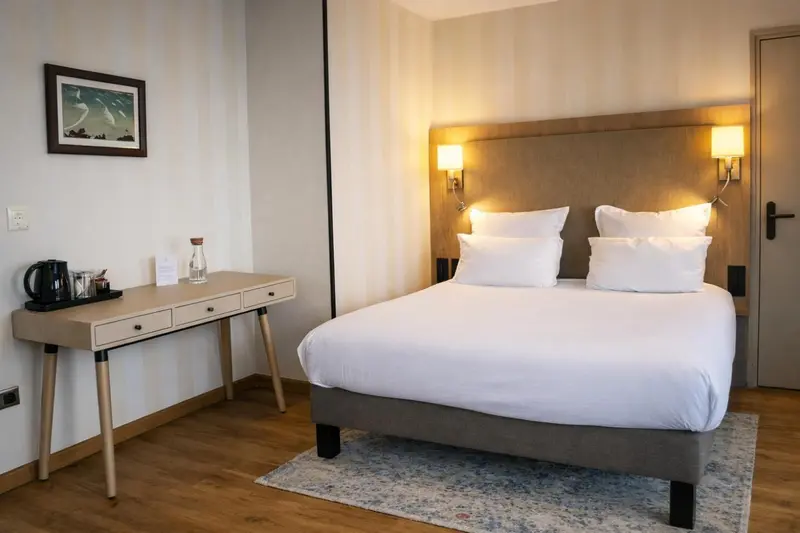 Une chambre lumineuse avec un grand lit et un bureau.