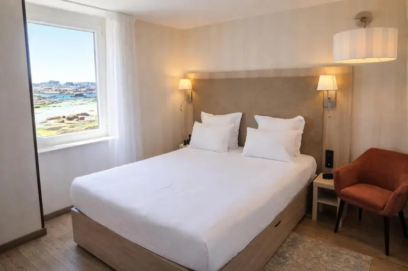 Une chambre lumineuse avec un grand lit et une vue sur la mer.