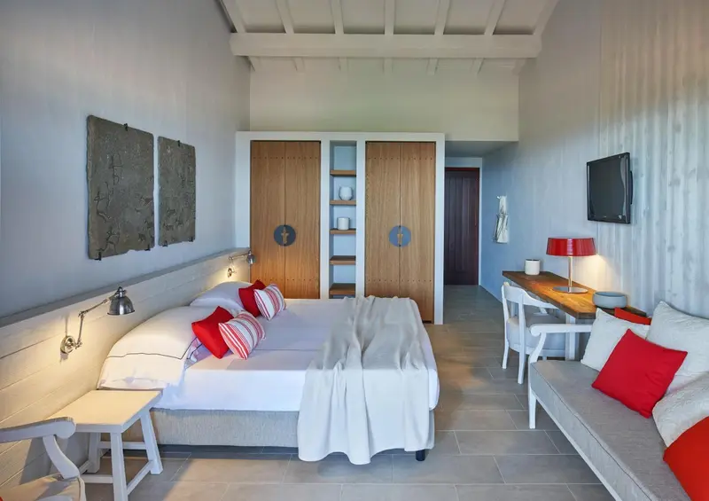 Une chambre lumineuse avec un lit double et un coin salon.