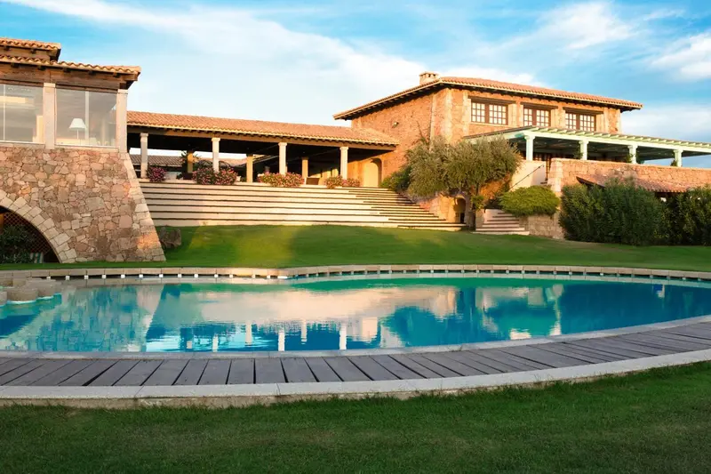 Bâtiment à l'architecture méditerranéenne avec piscine et pelouse verdoyante.