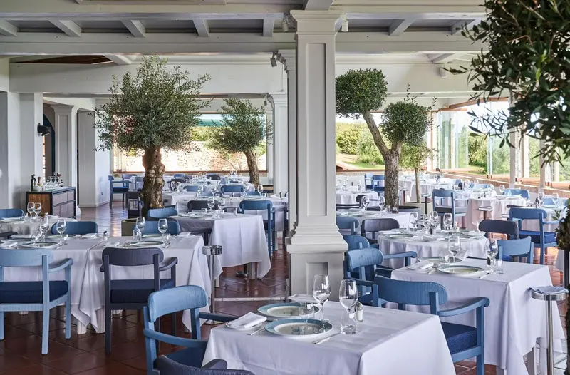 Une salle de restaurant lumineuse avec des tables dressées et une vue sur un jardin.