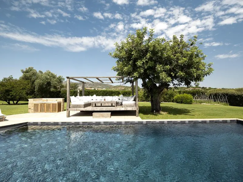 Espace de détente extérieur avec piscine et pergola ombragée.