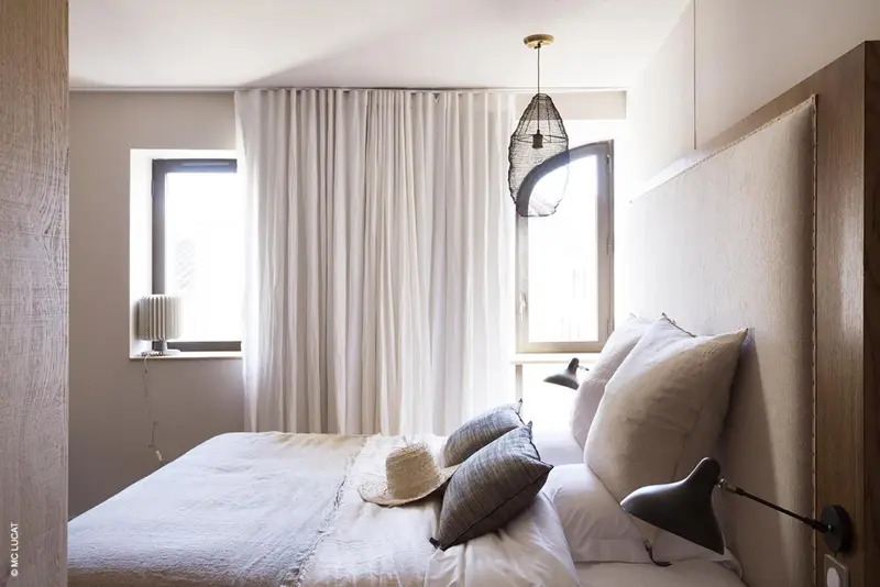 Une chambre lumineuse avec un grand lit et des rideaux blancs.